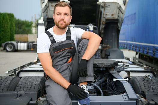 Semi Truck Under Maintenance. Caucasian Truck Mechanic Working to Fix the Tractor. photo