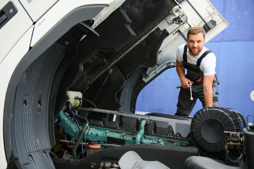 Semi Truck Under Maintenance. Caucasian Truck Mechanic Working to Fix the Tractor. photo