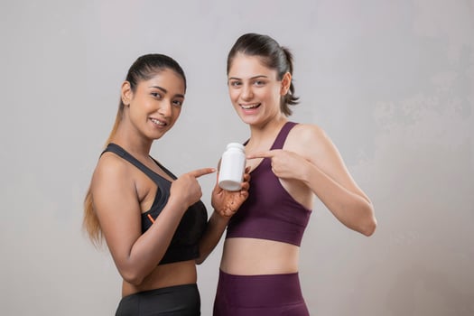 Two Cute Females Are Pointing Their Fingers At A Tablet Bottle While Looking At The Front Camera photo