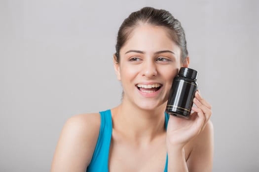 A Close-Up Of A Beautiful Hot Woman Smiling And Showing Her Black Tablet Bottle photo