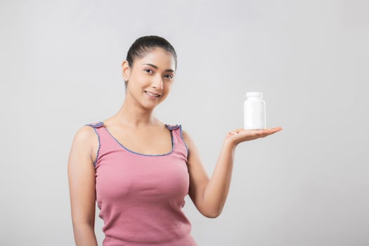 Pretty Brunette Woman In Pink Top Holding Vitamin Bottle photo