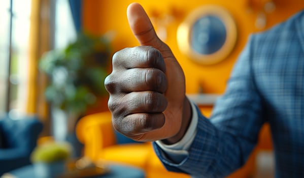 A man is giving a thumbs up gesture in front of a yellow wall. Concept of approval and positivity photo