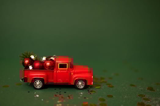 Red toy truck with Christmas balls and fir branch in its trunk. photo
