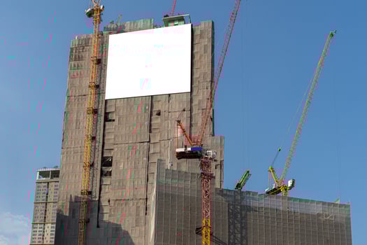 Blank information board hanging on the scaffoldings around the new building under construction. Warning signs at the bottom. photo