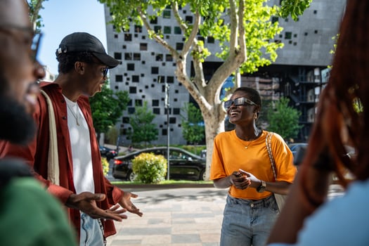 Nice meeting of happy African American friends outdoors on street, joyful students joking together. photo