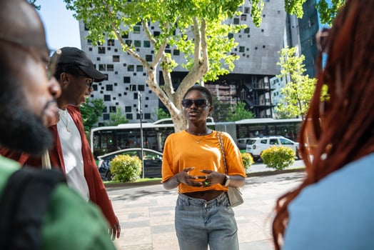 Excited african american girl student telling gossiping story to friends while standing on street. photo