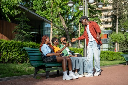 Pleasant meeting of calm relaxed African American students friends in park, sitting on alley bench photo