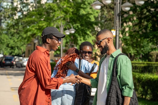 Cheery, joyous African-American friends enjoying sudden pleasant meeting at street outdoors outside photo