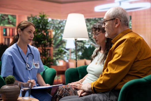 Medical assistant comforting elderly man and woman at home, emphasizing nursing support and personal care assistance for senior living. Social caretaker giving advice to old couple. photo