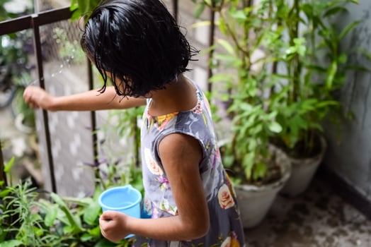 Cute 5 year old Asian little girl is watering the plant in the pots located at house balcony, Love of sweet little girl for the mother nature during watering into plants, Kid Planting photo