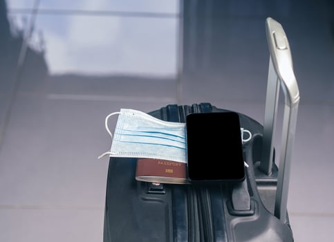 A smartphone on mask and passport placed on suitcase. Space for text. Technology, journey and healthcare concept photo