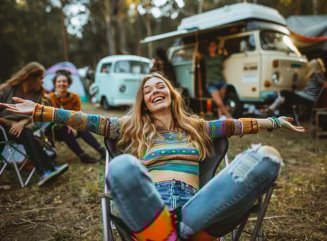 Young woman is sitting on a chair with her arms outstretched and having fun on a camping background during a music festival. The concept of leisure activities. photo