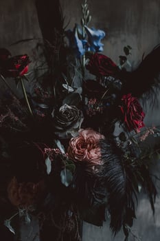 Dark and Moody Floral Arrangement with Roses and Feathers in Low Light photo