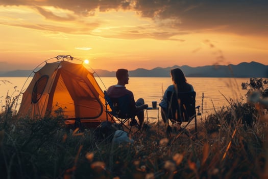 A couple of tourists admire the sunset in nature near the sea. Camping concept for outdoor activities, summer travel and camping in the mountains. photo