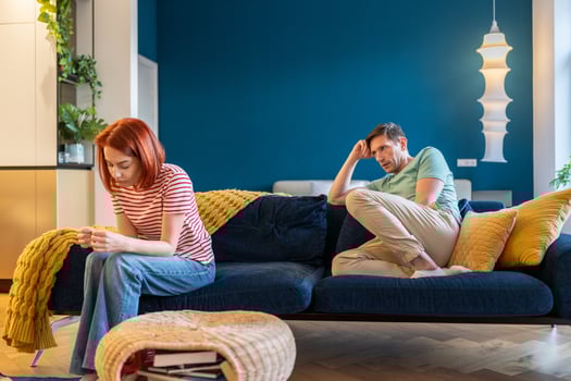Upset European family couple wife and husband sit separately on sofa at home not talking after fight photo