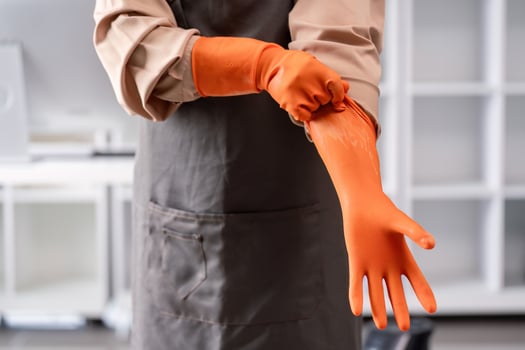 Professional Maid or Housekeeper Wearing Orange Gloves and Apron Ready for Cleaning Duties in a Modern Home Environment photo