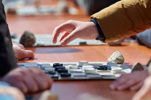Outdoor draughts competition on paper checkerboard on table, close up players hands photo