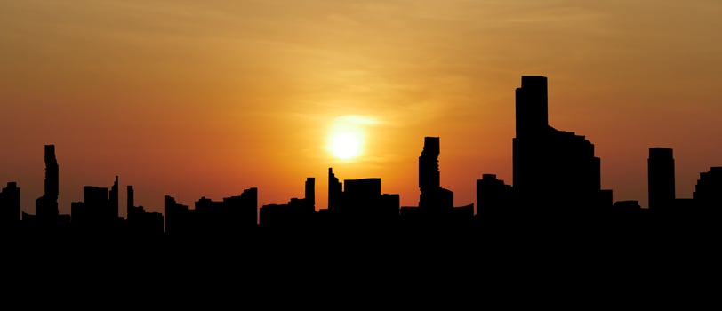 Silhouette of Modern City Skyline at Sunset with Orange and Yellow Sky photo