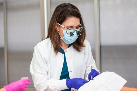 Skin lesion removal procedure. Dermatologist carrying out a removal of benign skin lesion on the face of a young male patient. photo