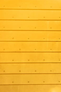 Corrugated metal background in yellow color. The texture of horizontal metal plates connected by rivets. Blank for a poster or banner. photo