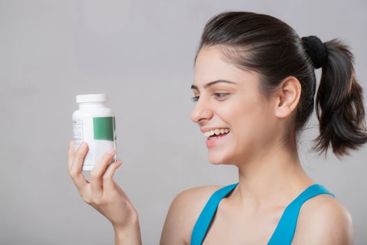 Gorgeous Blonde Woman Posing Sideways With A Medicine Bottle photo