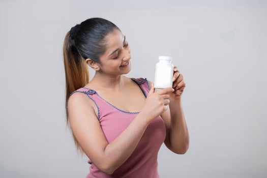 Beautiful Intelligent Woman Lovingly Looking At White Bottle photo