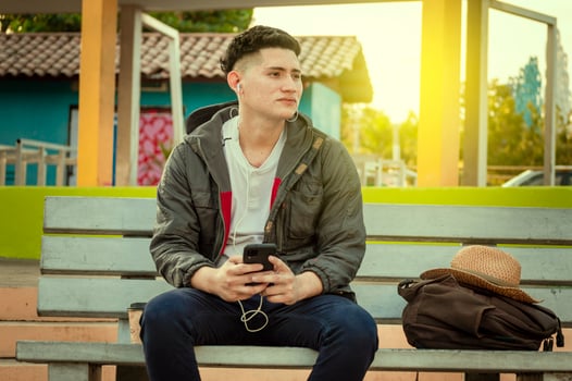 Attractive guy listening to music on a bench. Handsome man sitting on a bench listening to music with phone photo