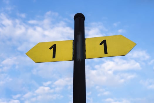 Yellow direction sign on the pole against the blue sky. Yellow arrow signal against sky. photo