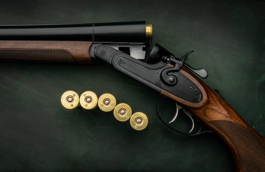 Classic trigger double-barreled hunting rifle on a green background. Smooth-bore hunting rifle open for reloading. Concept postcards for hunters. photo