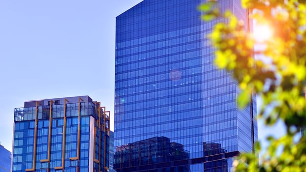 City life, urban landscape and ecology. Modern office complex with glass facades and smooth lines against backdrop of green trees, concept of modern architecture. Organically building into nature. photo