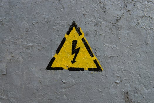 The sign of electrical hazard on a gray coarse metaic painted surface photo