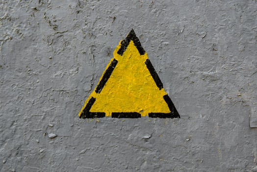 Yellow triangle on a old gray coarse metaic painted surface photo
