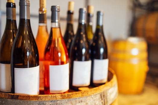 Close up of mockup of group of glass bottles with different wines and champagne on wooden wine barrel photo