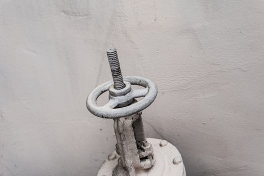Old industrial valve on light background. A metal pipeline valve, old weathered gas crane and pipe .Old valves have rust, Circular handle, Old valves assembled with steel pipes. photo