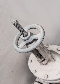 Old industrial valve on light background. A metal pipeline valve, old weathered gas crane and pipe .Old valves have rust, Circular handle, Old valves assembled with steel pipes. photo