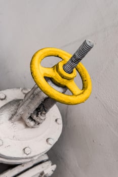 Old industrial valve on light background. A metal pipeline valve, old weathered gas crane and pipe .Old valves have rust, Circular handle, Old valves assembled with steel pipes. photo