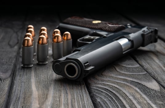 Pistol and cartridges for it on a wooden back. A short-barreled weapon for self-defense. photo