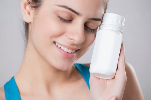 Model Close Up Shot Holding Vitamin Capsule Bottle In Hand photo