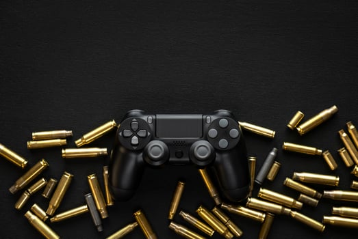 Modern black gamepad on a black background among the spent cartridges. Game concept. Shooter game. photo