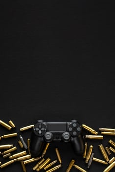 Modern black gamepad on a black background among the spent cartridges. Game concept. Shooter game. photo