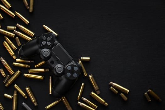 Modern black gamepad on a black background among the spent cartridges. Game concept. Shooter game. photo