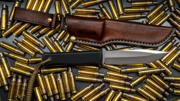 A modern military or hunting knife against a background of gun cases. photo