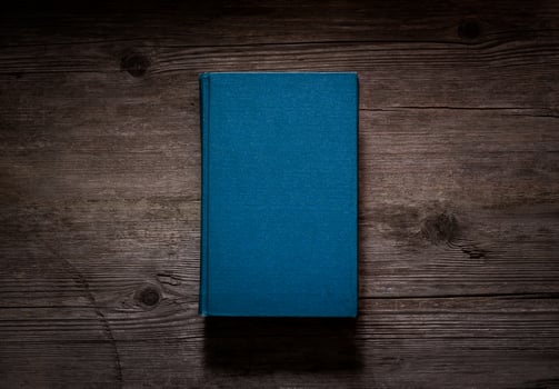 Closed book on vintage wooden background. Old book on the wooden table. Closed book with empty cover laying on wooden table. photo
