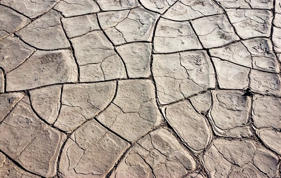 Dry yellow clay cracked in the sun with sand in the Californian desert, Death Valley National Park, California photo
