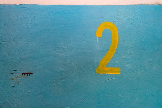 Yellow number two on the blue painted wall photo