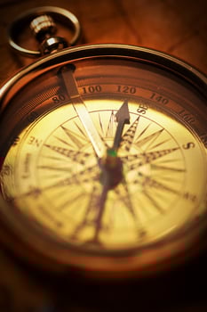 Close-up of an antique compass bathed in a warm glow, showcasing its intricate scale and patina, embodying the spirit of exploration and history. photo