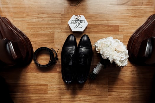 A man's wedding shoes and a bouquet of flowers are displayed on a wooden table photo