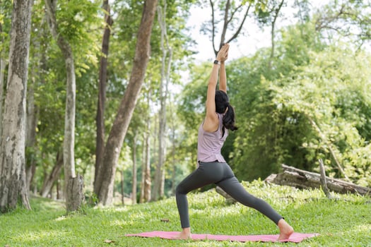 Young Woman Practicing Yoga in a Serene Park Setting Surrounded by Lush Greenery and Trees photo