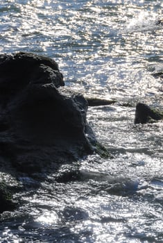 Bright reflections on the water on a sunny day among the coastal rocks near the Black Sea coast photo