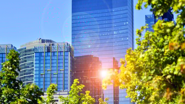 City life, urban landscape and ecology. Modern office complex with glass facades and smooth lines against backdrop of green trees, concept of modern architecture. Organically building into nature. photo